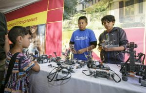 Anthony Romano, left ,and Dylan Manzano, sixth graders at Foshay Learning Center, demonstrate robots to Alice Montoya, 5, in the Civic Engagement Tent at the Los Angeles Times Festival of Books at USC April 18, 2015. Photo by David Sprague